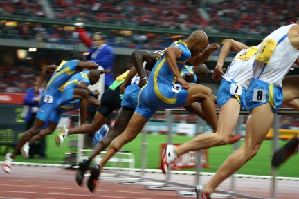 runners going over hurdles